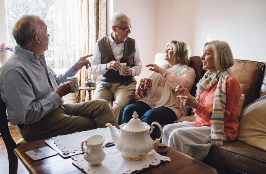 A group of seniors sitting a common room, enjoying a pot of tea and socializing
