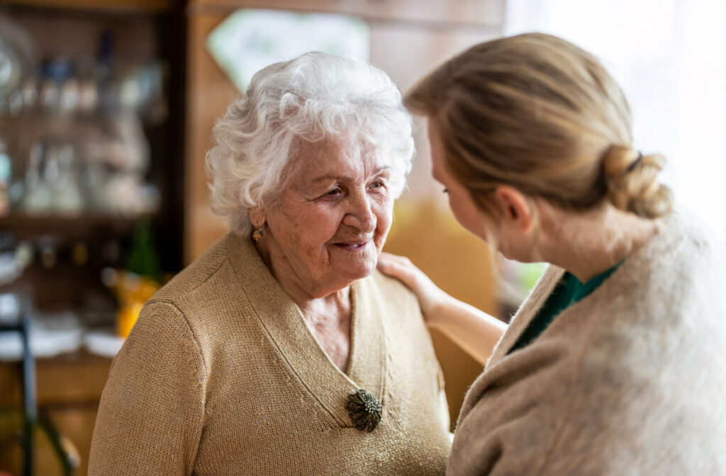 A caregiver talking to an older adult woman with dementia in a senior living community
