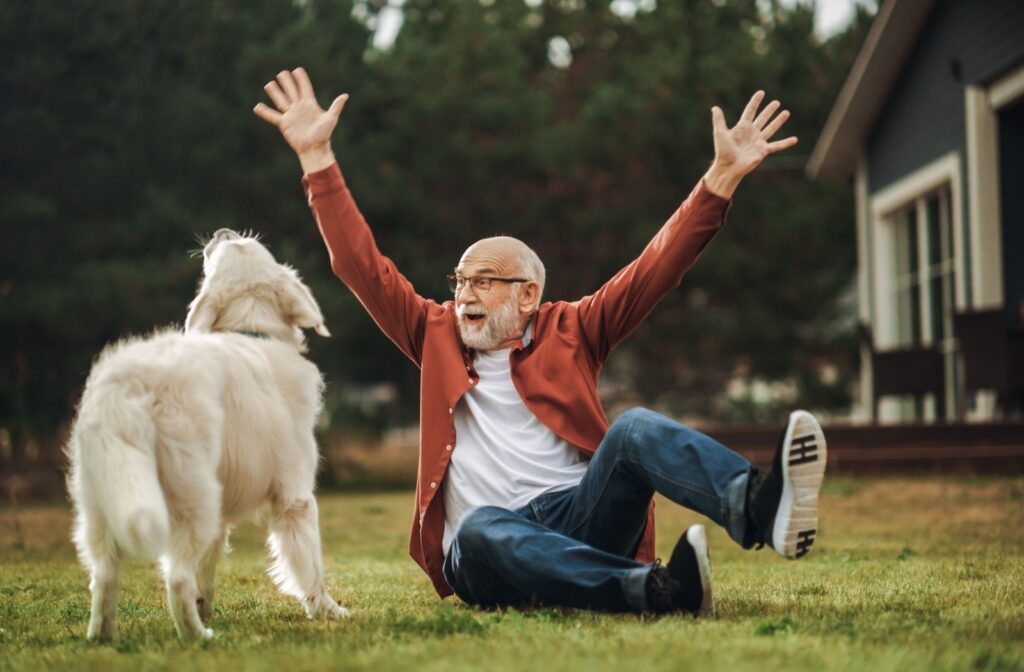 An older adult man playing with a his dog outdoors
