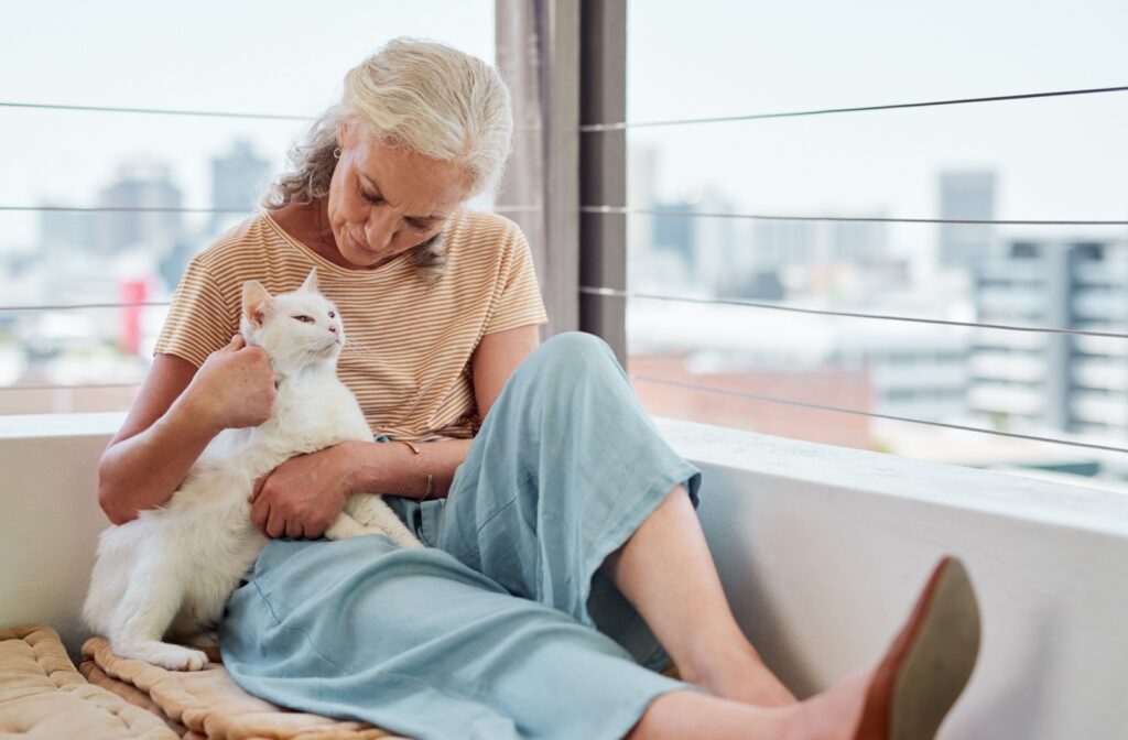 An older adult woman holding a white cat at home
