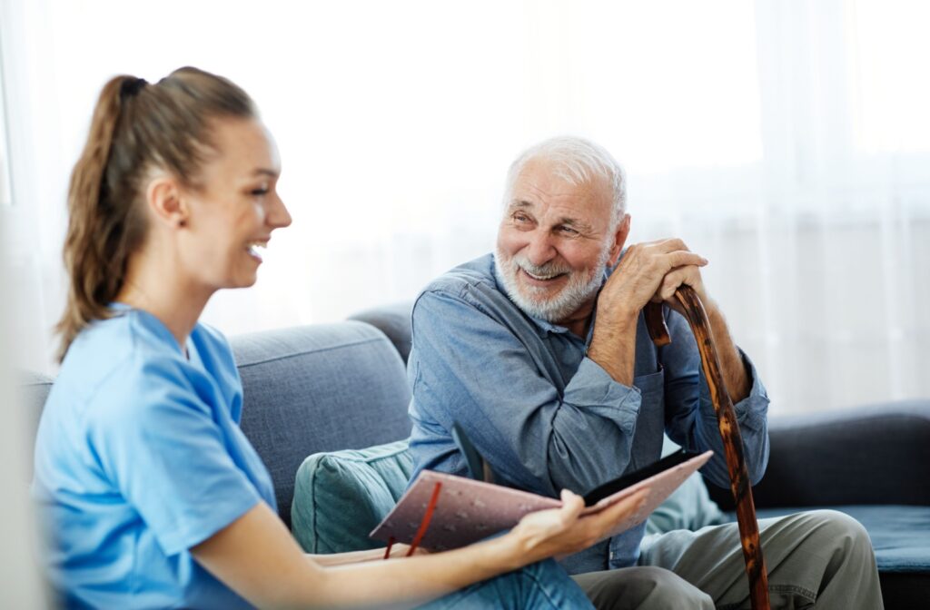 A senior man in memory care laughing with a nurse.