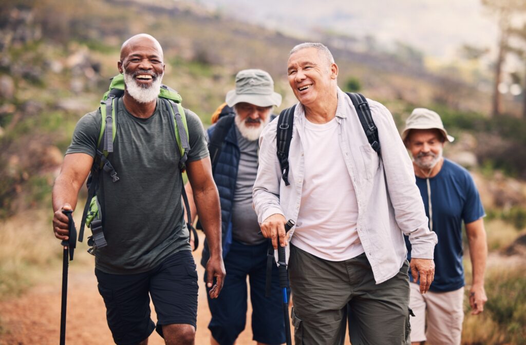 A group of older men smiling and hiking outdoors.